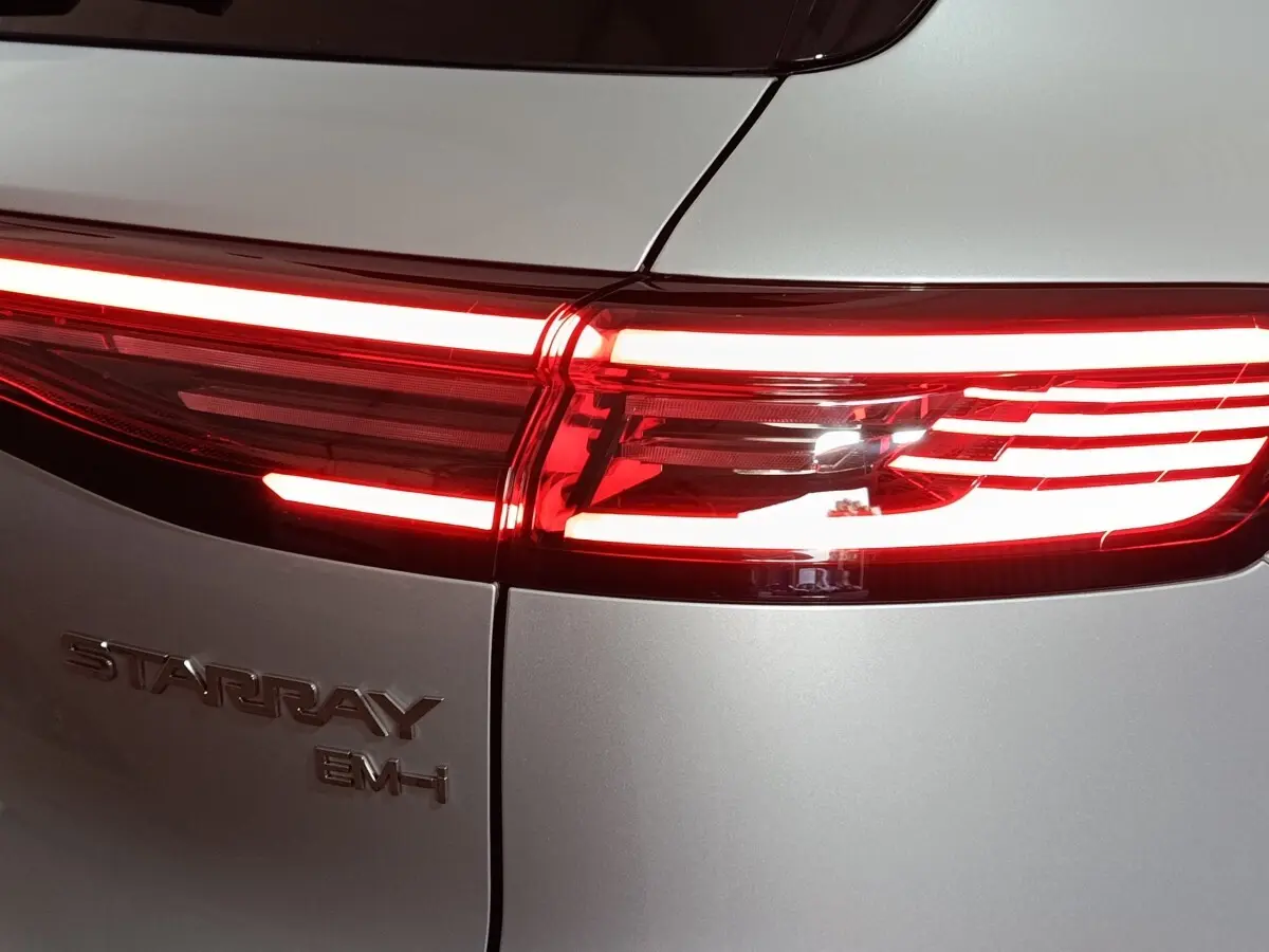 Gros plan sur le feu arrière droit rouge allumé d’un Geely STARRAY gris clair avec logo et badge EM-I visible.