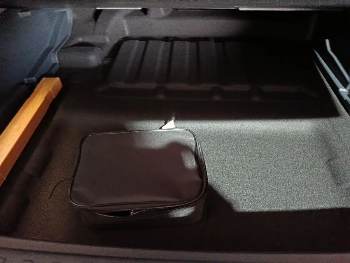 Vue intérieure du coffre gris clair du Geely STARRAY 1.5 EM-I PHEV Max+ avec trousse noire et rangement latéral orange.