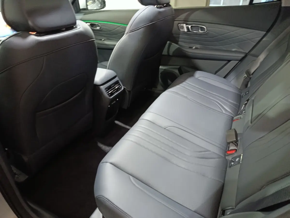 Vue intérieure arrière côté droit du Geely STARRAY 1.5 EM-I PHEV Max+ gris clair, sièges en cuir noir et accoudoir central.
