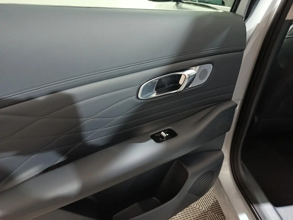 Gros plan sur la porte avant droite gris clair du Geely STARRAY 1.5 EM-I PHEV Max+ avec poignée et commande de vitre.