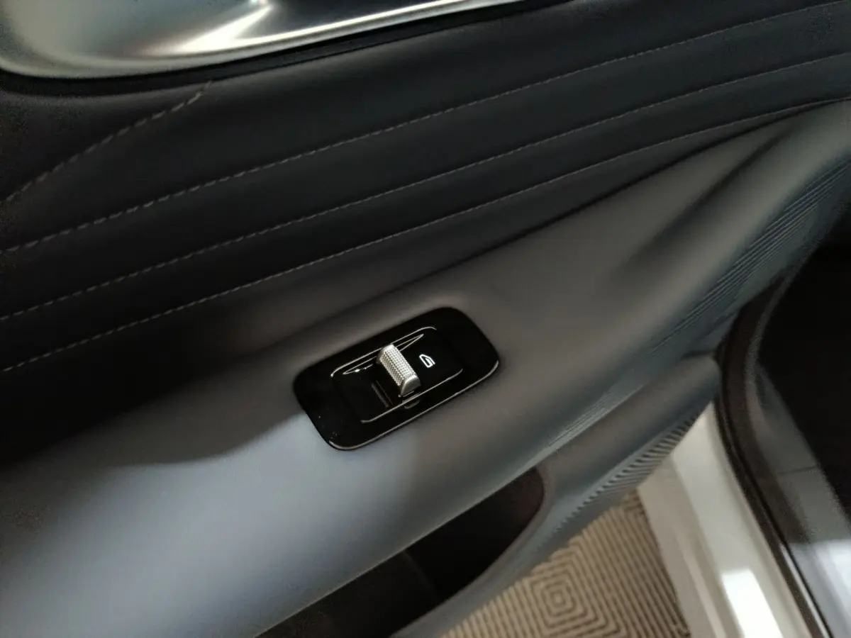 Détail du bouton de commande de la vitre sur la porte intérieure côté droit du GEELY STARRAY gris clair.