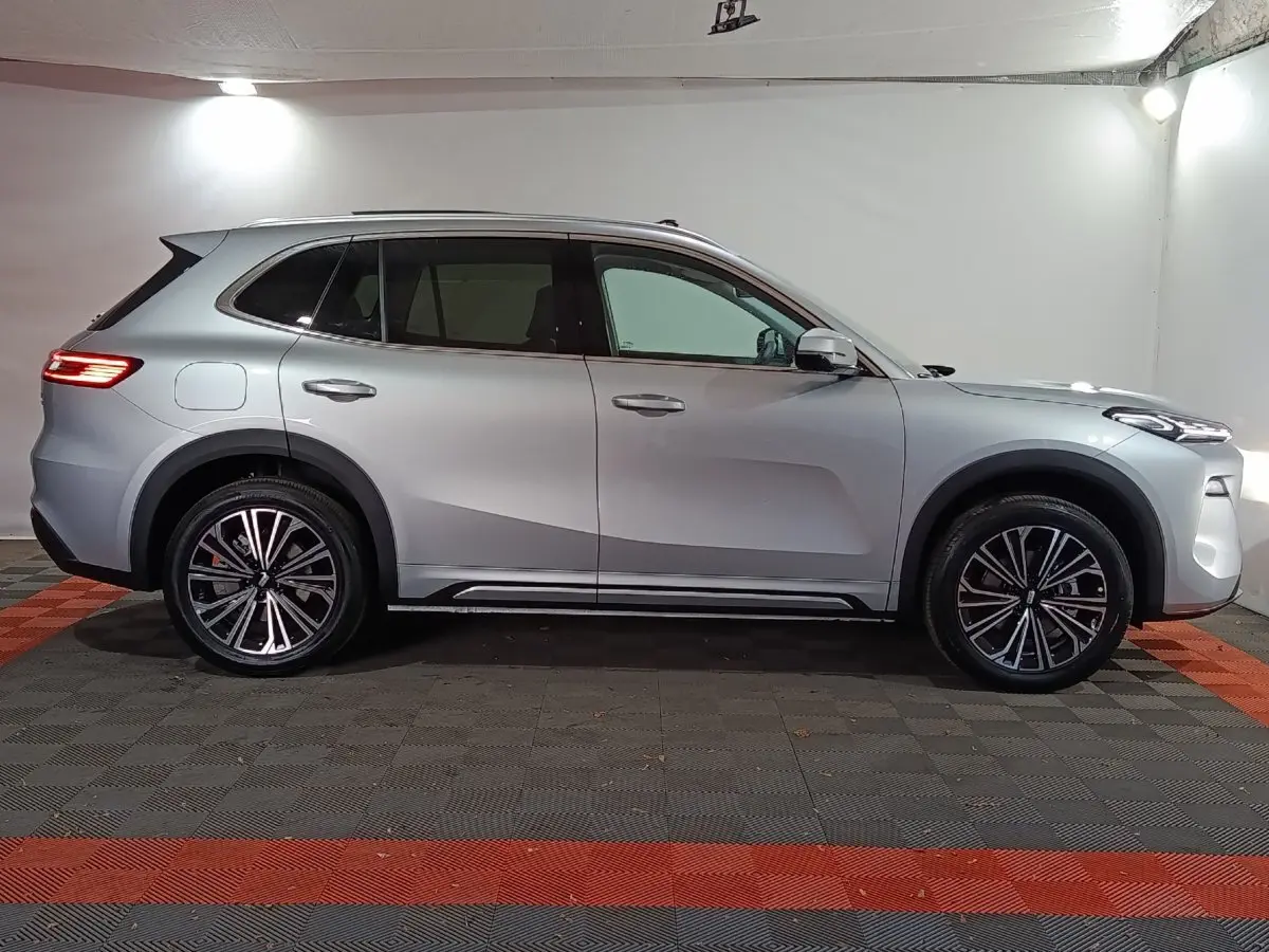 Vue de profil côté gauche d’un SUV Geely STARRAY gris clair 2026 avec jantes alliage et toit vitré.