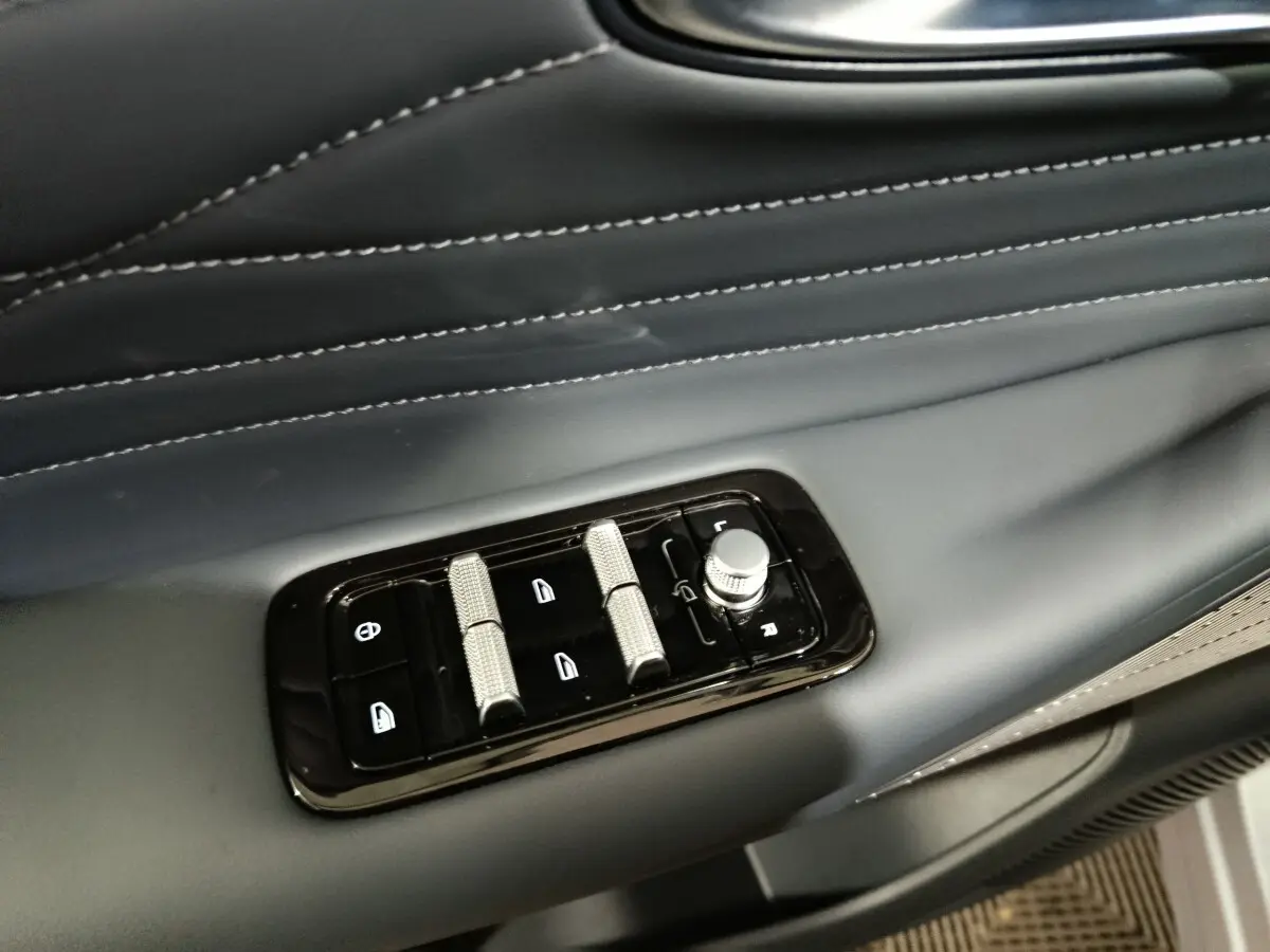 Détail des commandes de réglage des vitres et des rétroviseurs sur la porte côté gauche en cuir noir du Geely STARRAY 2026.