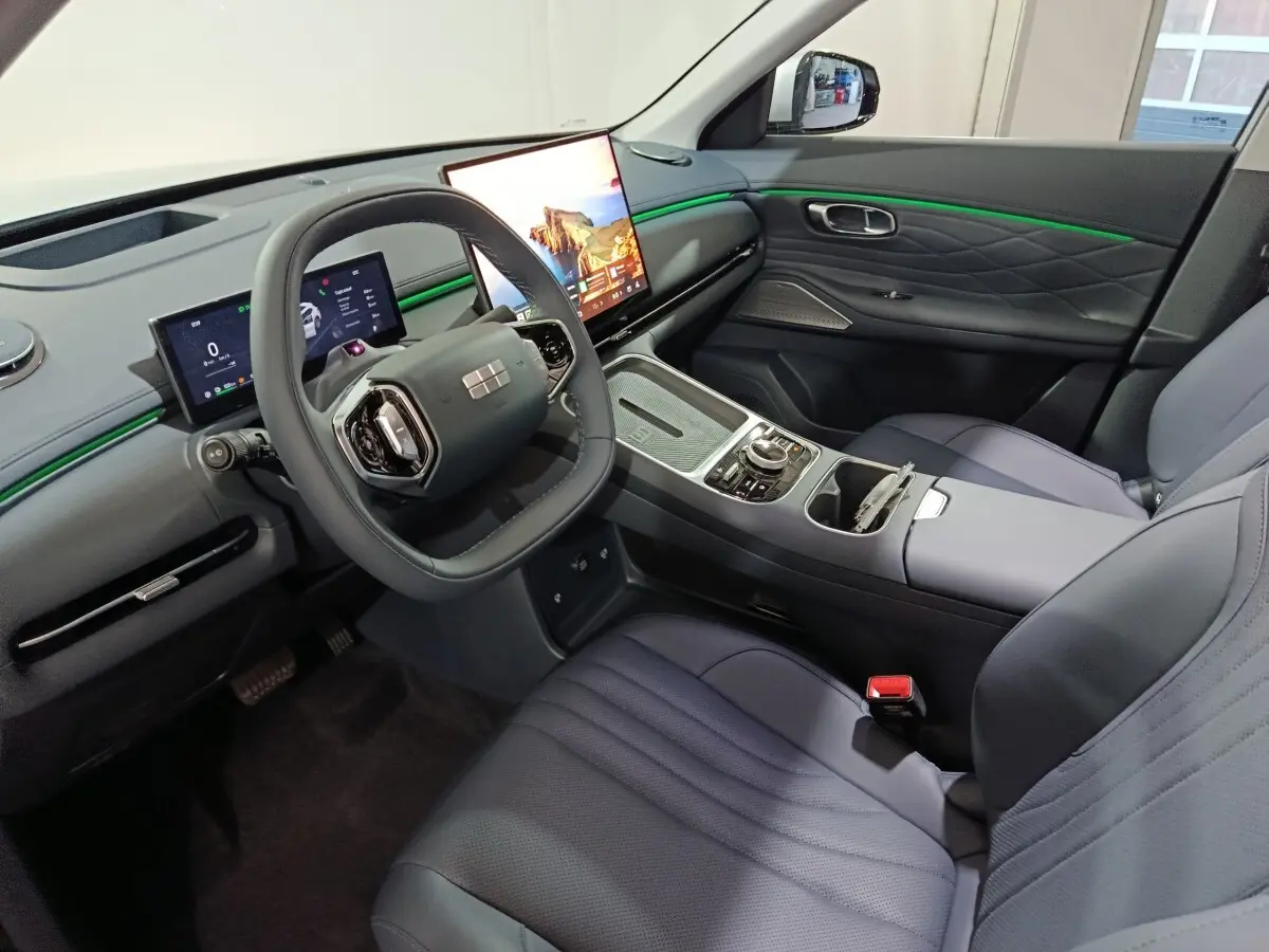 Intérieur avant droit du Geely STARRAY gris clair, tableau de bord avec écrans tactiles et éclairage d’ambiance vert.