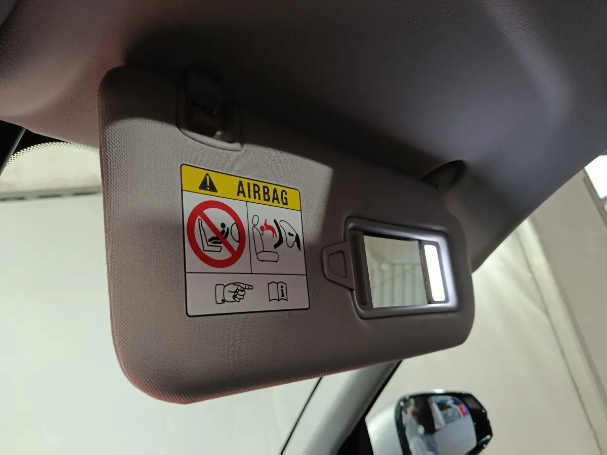 Détail intérieur du pare-soleil côté conducteur avec miroir éclairé et avertissement airbag dans un Geely Starray gris clair.