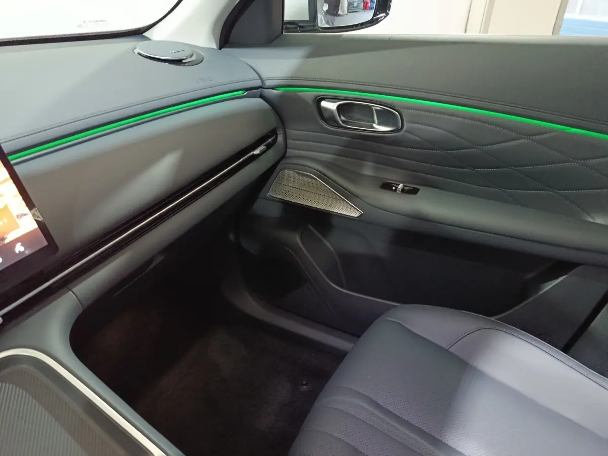 Intérieur côté passager du Geely STARRAY 1.5 EM-I PHEV Max+ avec éclairage d'ambiance vert et sellerie grise.