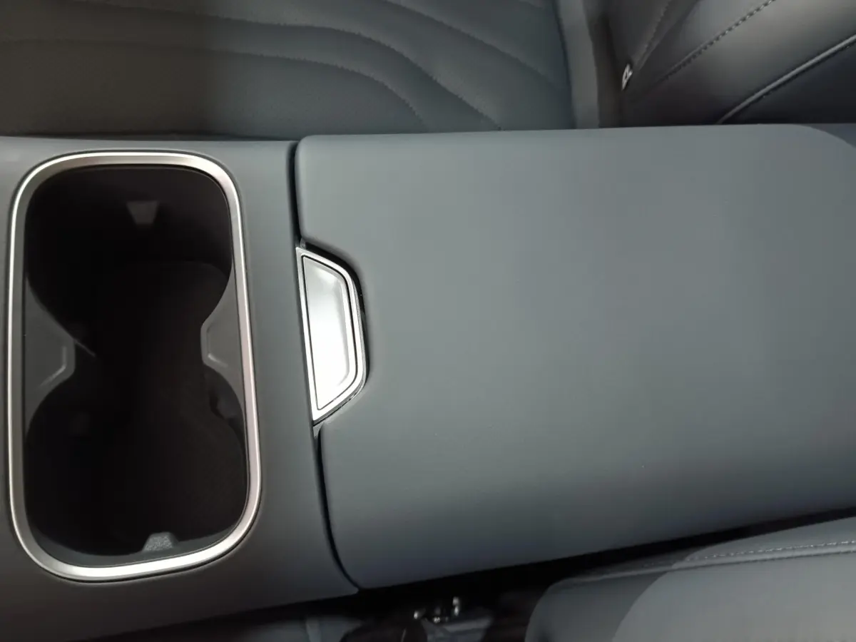 Gros plan sur l'accoudoir central gris clair avec porte-gobelets chromé intérieur d'un GEELY STARRAY 1.5 EM-I PHEV Max+