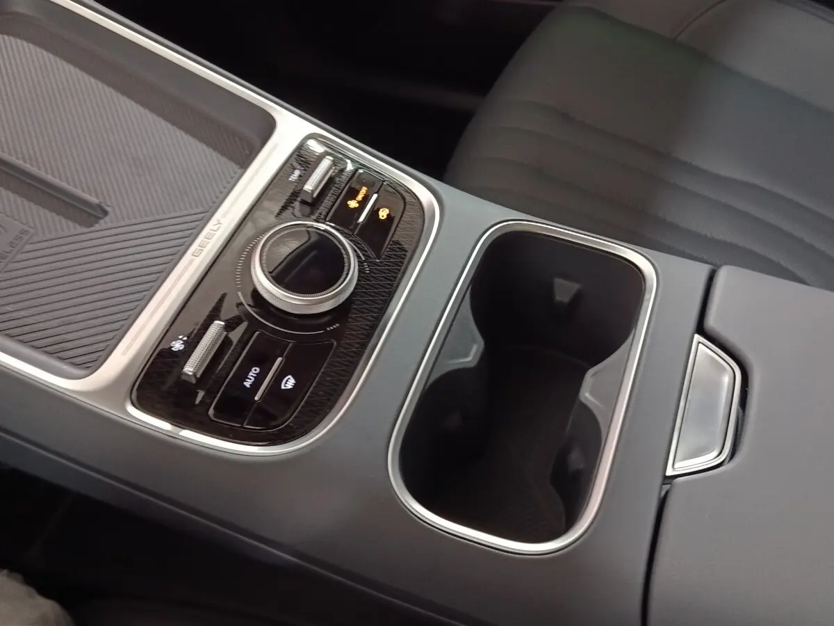 Gros plan sur la console centrale grise du Geely STARRAY 1.5 EM-I PHEV Max+ avec molette de sélection et porte-gobelets.