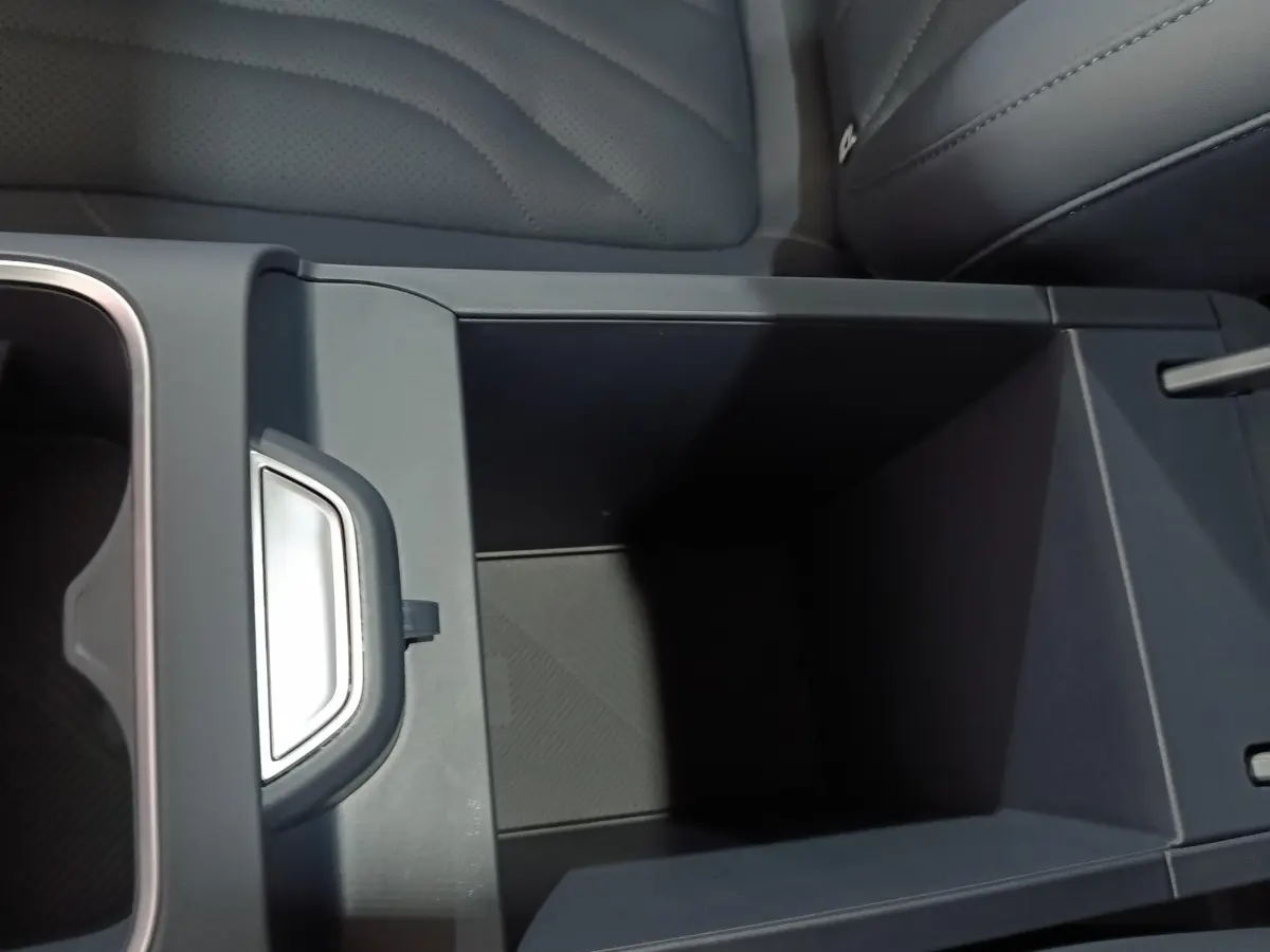 Vue rapprochée de l'accoudoir central arrière gris foncé du Geely STARRAY 1.5 EM-I PHEV Max+ avec rangement ouvert.