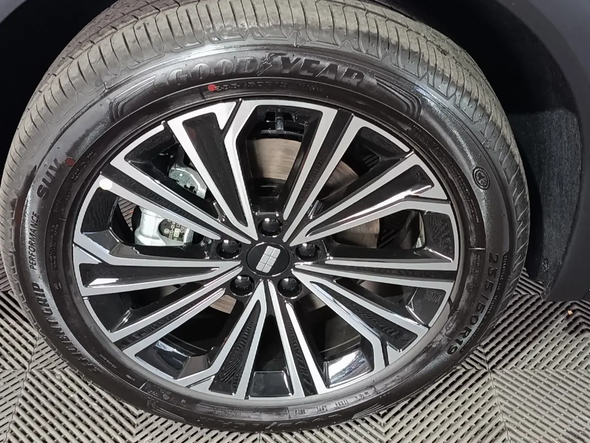 Gros plan sur la jante noire et argentée d’un Geely STARRAY gris clair, montrant le pneu Goodyear et le logo central.