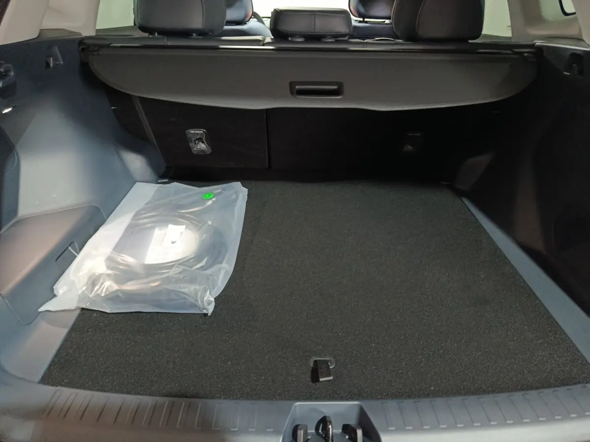 Coffre ouvert du Geely STARRAY gris clair, vue intérieure montrant la banquette arrière et un câble de recharge emballé.
