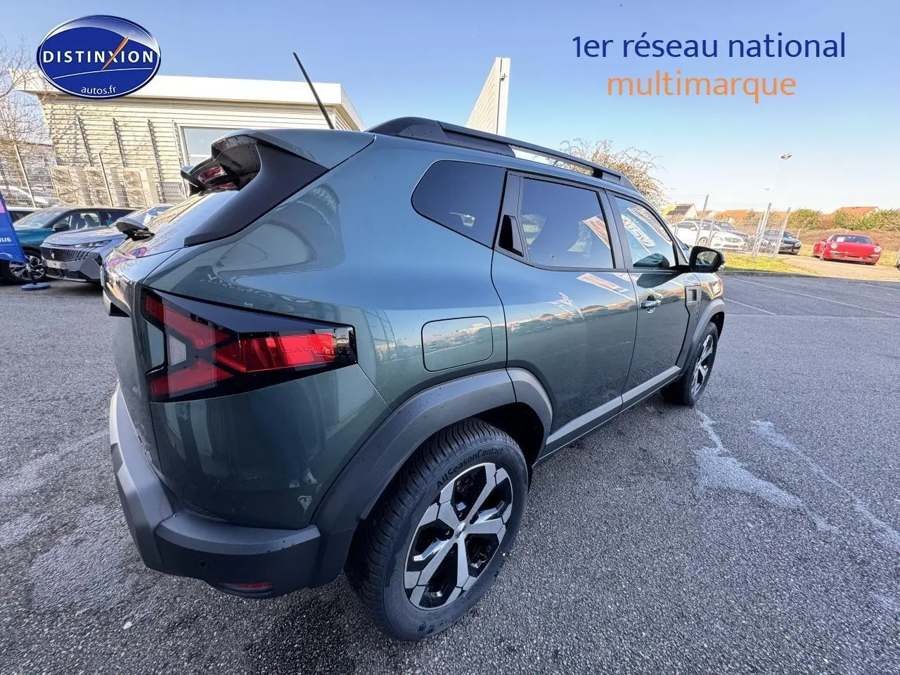 Vue 3/4 arrière droite d'un Dacia Duster 2025 vert cèdre avec barres de toit et jantes alu noires.