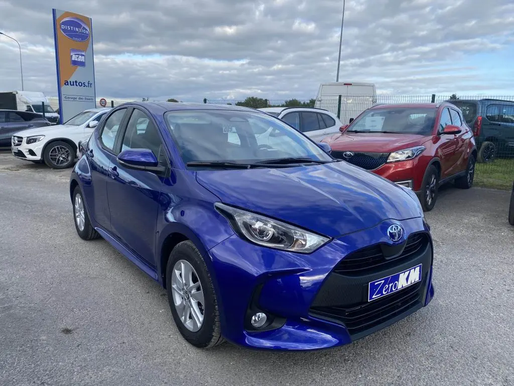 Toyota Yaris hybride 2025 bleu Genièvre vue 3/4 avant avec jantes alliage 15 pouces et calandre noire distinctive.