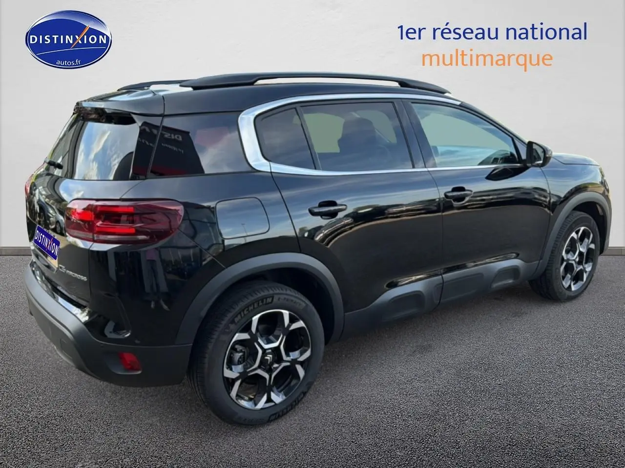 Vue 3/4 arrière droite du Citroën C5 Aircross noir Perla Nera avec barres de toit et jantes alu distinctives.