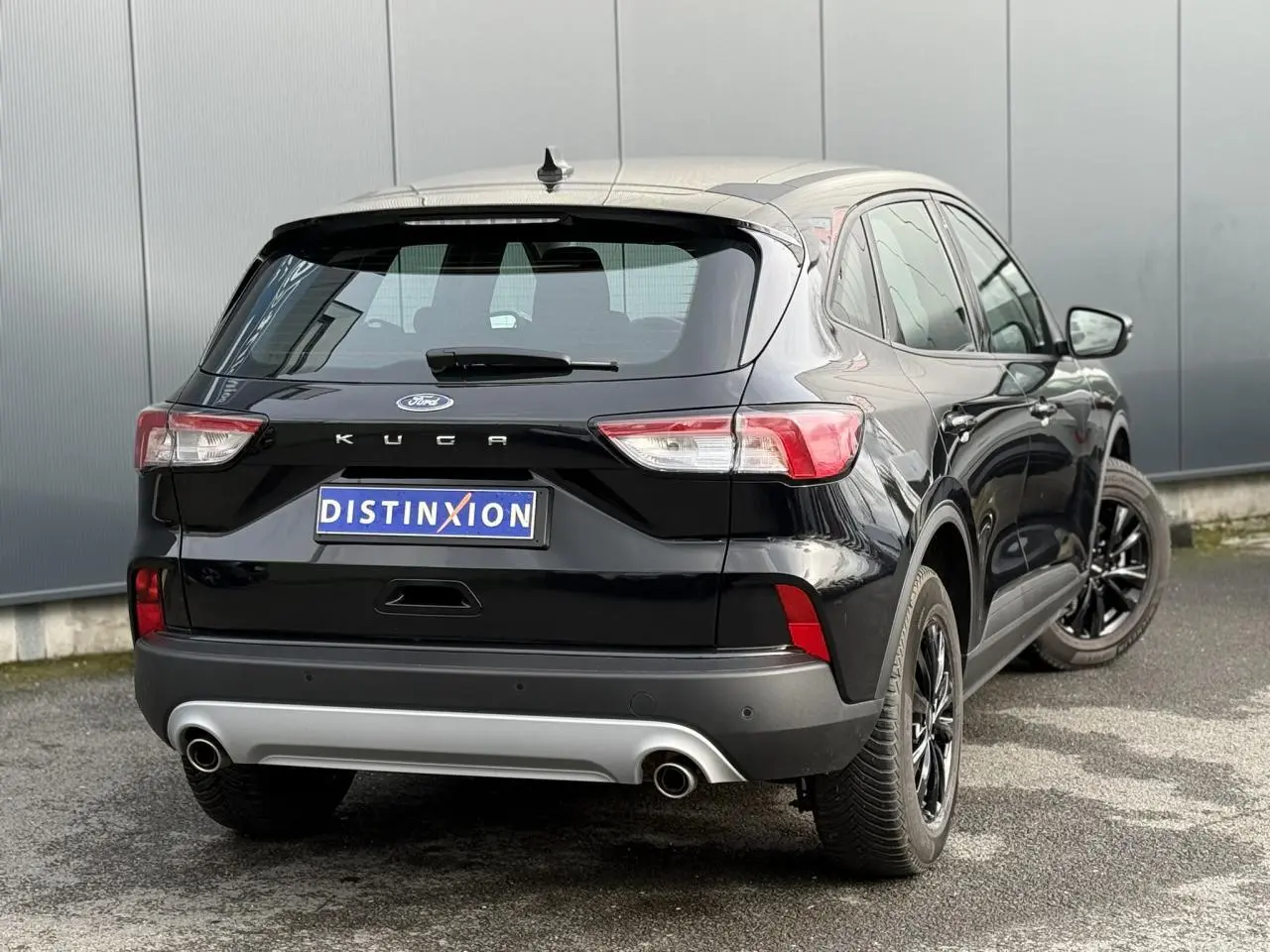 Vue 3/4 arrière droite du Ford Kuga 2024 noir Obsidien avec attelage rétractable et jantes alliage noires.