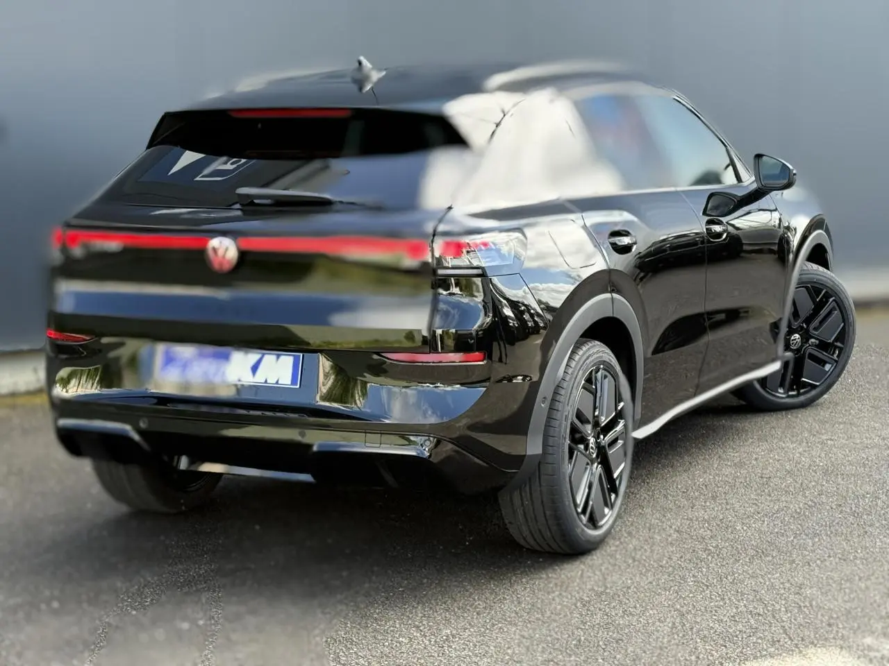 Volkswagen T-Roc noir ébène en 3/4 arrière droit, avec jantes noires et bandeau lumineux arrière distinctif.