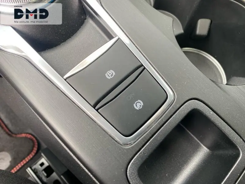 Gros plan sur la console centrale noire du Ford Kuga 2026, montrant les boutons de frein à main électronique et d'assistance au stationnement.