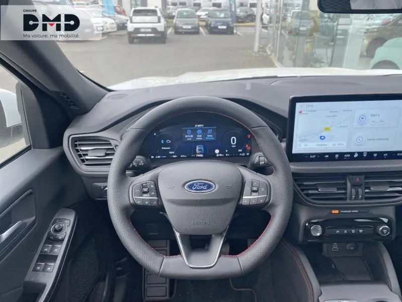 Vue intérieure centrée sur le volant et le tableau de bord numérique du Ford Kuga blanc Glacier, avec écran tactile et commandes au volant.