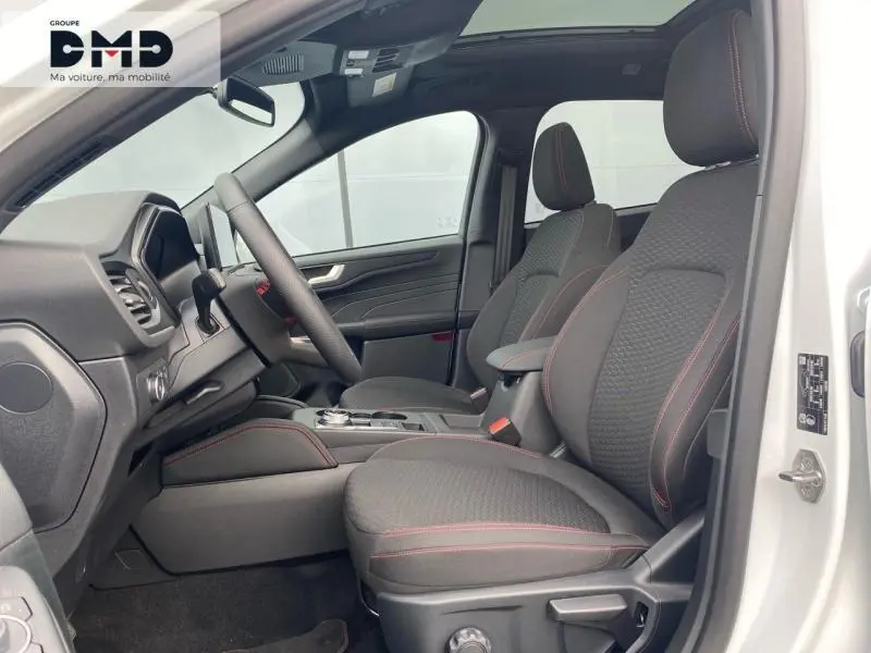 Vue intérieure côté conducteur du Ford Kuga blanc glacier 2026, sièges tissu noir avec surpiqûres rouges et toit ouvrant panoramique.