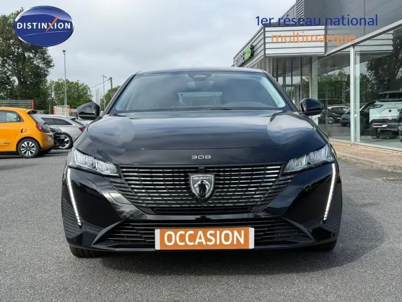 Vue avant d'une Peugeot 308 2024 noire Perla Nera avec calandre moderne et feux LED en position allumée.