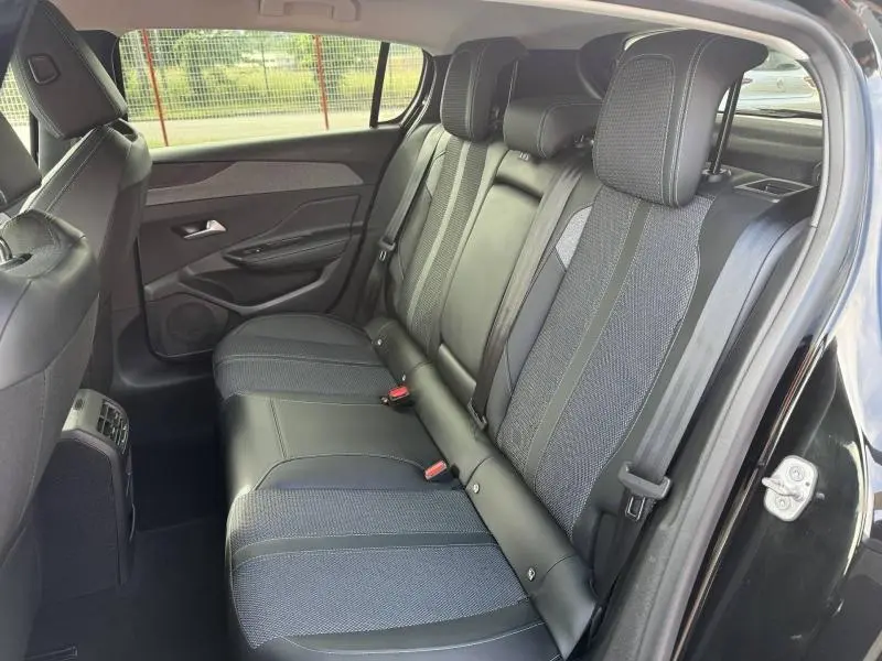 Vue côté droit de l'intérieur arrière de la Peugeot 308 2024 noir Perla Nera, sièges mixtes cuir et tissu avec appuie-têtes.