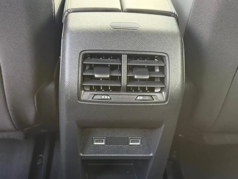 Vue rapprochée des aérateurs arrière noirs et des ports USB de la console centrale d'une Peugeot 308 noire.