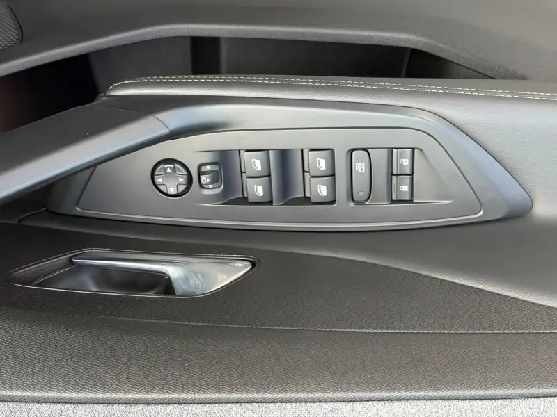 Vue rapprochée de la commande des vitres et rétroviseurs côté conducteur du PEUGEOT 308 2024 en noir Perla Nera.