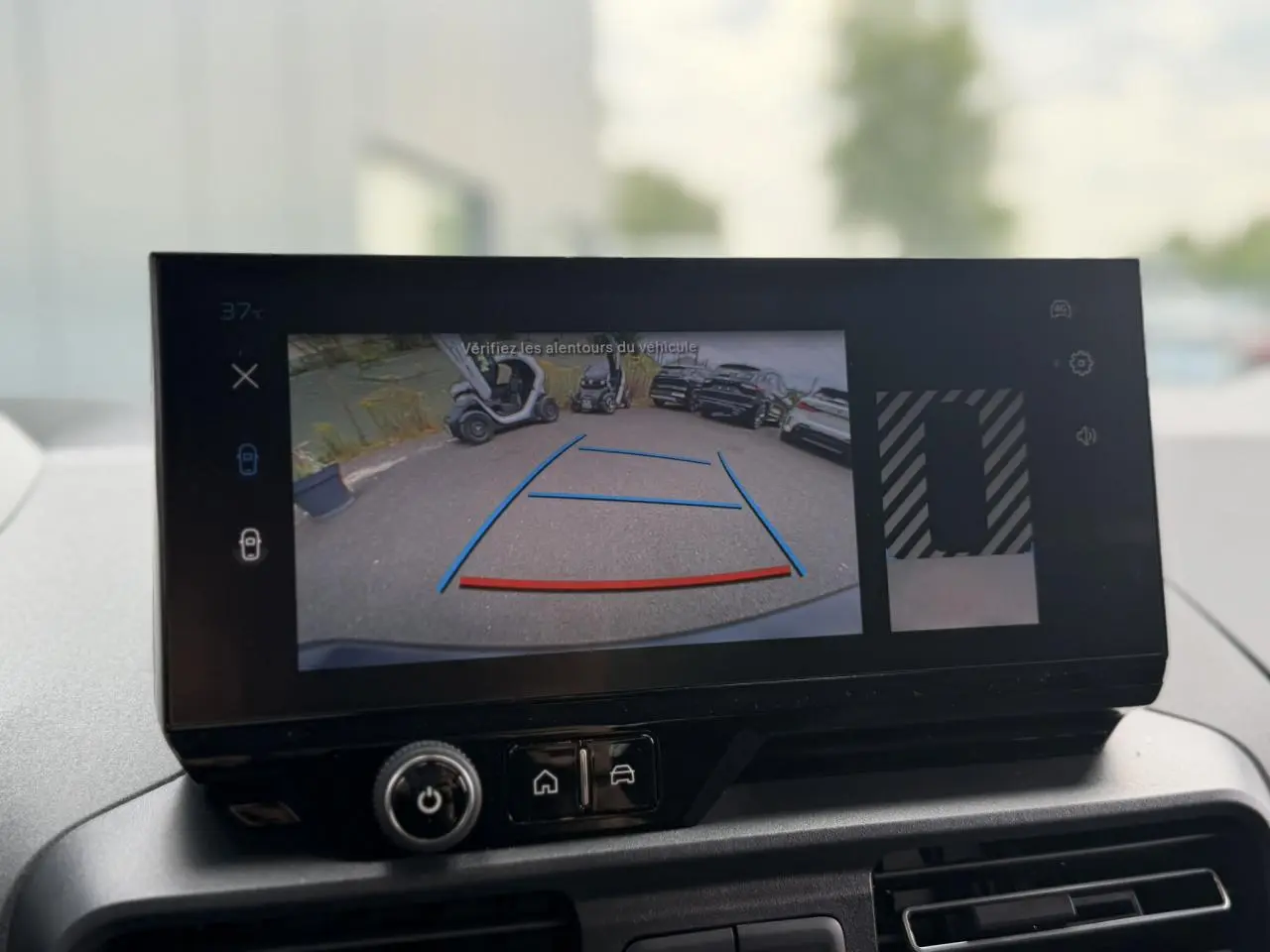 Écran tactile intérieur montrant la caméra de recul du Peugeot Rifter vert Sirkka, vue arrière avec lignes de guidage colorées.