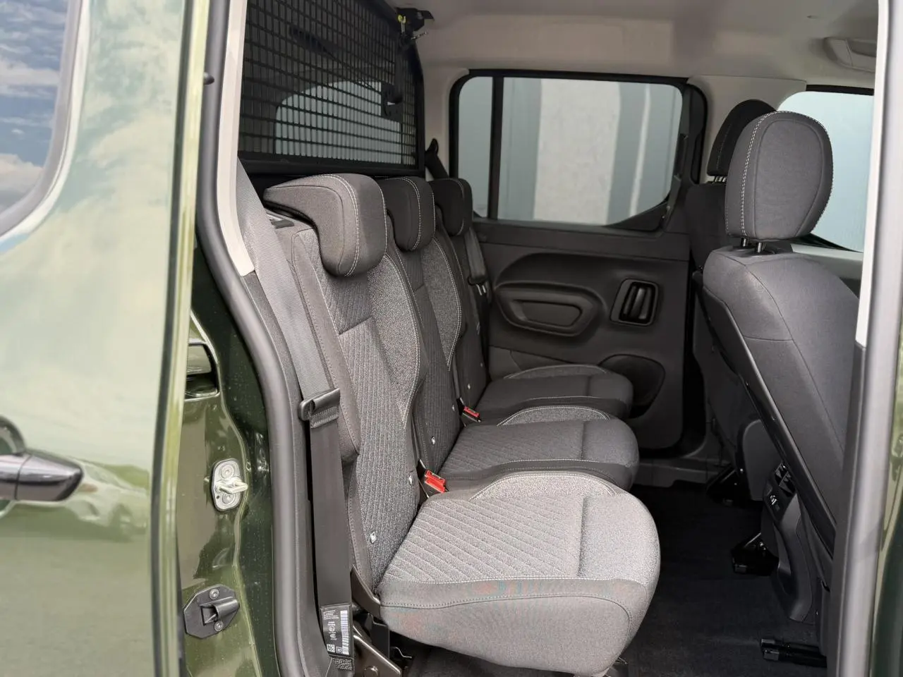 Vue intérieure côté gauche du Peugeot Rifter vert Sirkka montrant les trois sièges individuels arrière en tissu gris.