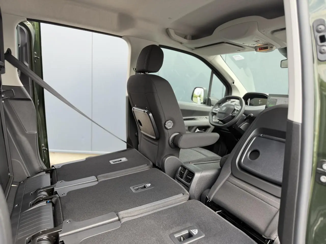 Vue intérieure côté droit du Peugeot Rifter Vert Sirkka 2026, sièges arrière rabattus et siège avant conducteur avec tablette.