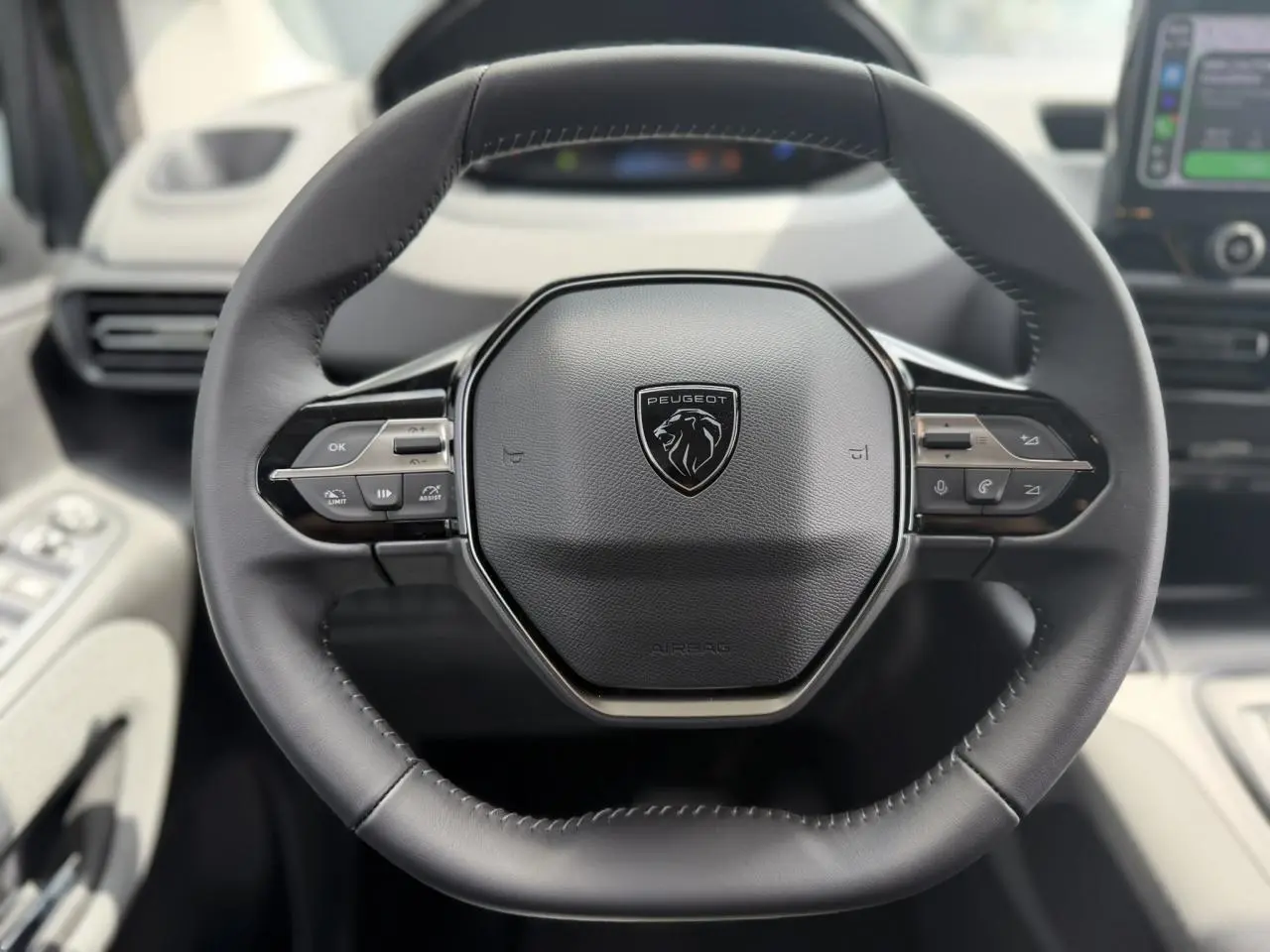 Vue rapprochée du volant cuir noir du Peugeot Rifter 2026 avec commandes multifonctions et logo lion central.