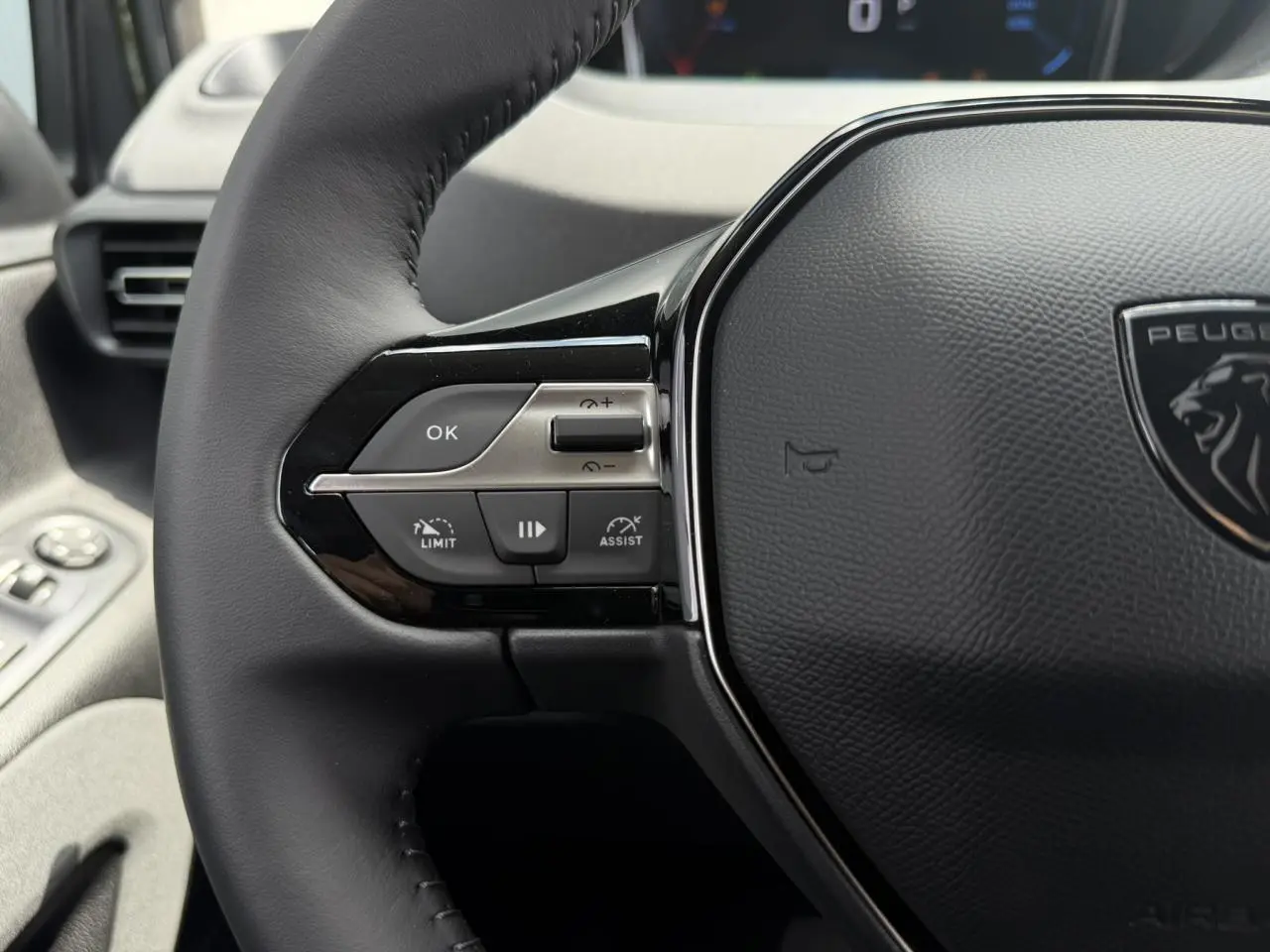 Gros plan sur le volant cuir multifonction du Peugeot Rifter 2026, avec commandes intégrées et logo lion central.