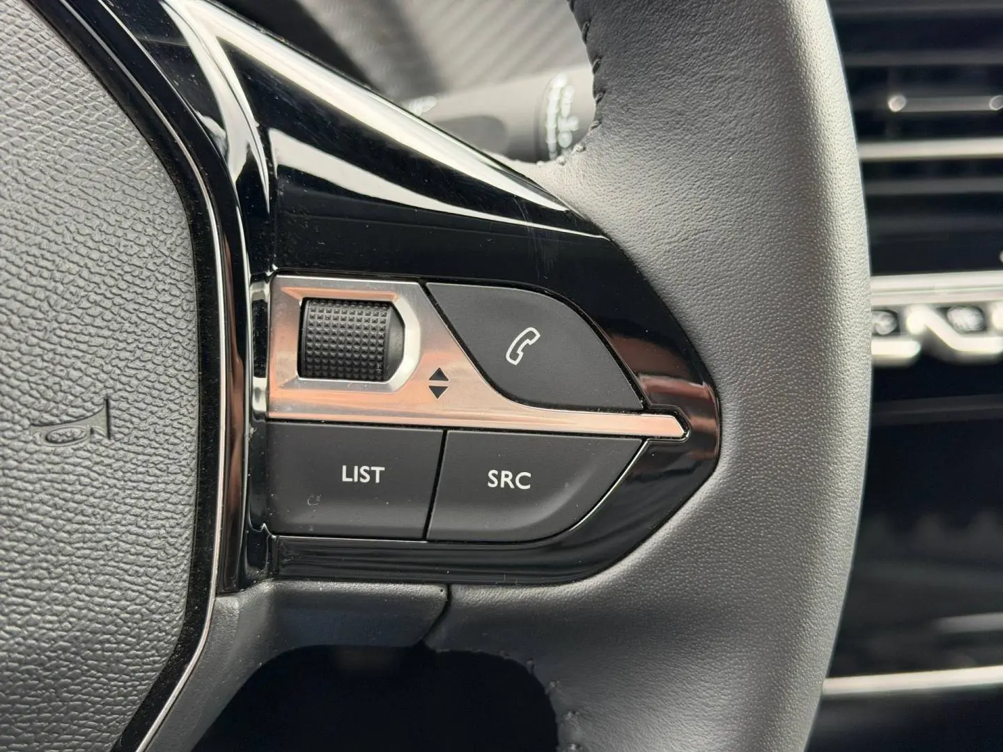 Gros plan sur les commandes noires du volant côté gauche du Peugeot 208 1.2 100ch Allure noir Perla Nera.