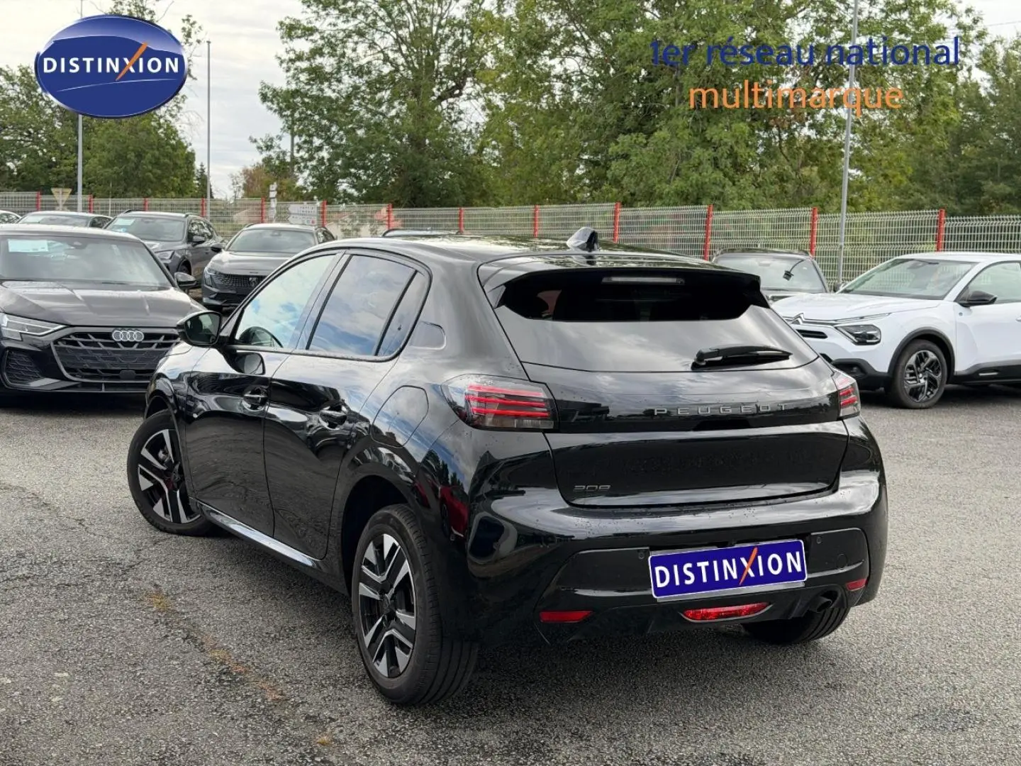 Vue 3/4 arrière d’une Peugeot 208 noire Perla Nera avec vitres teintées et jantes alu en parking.