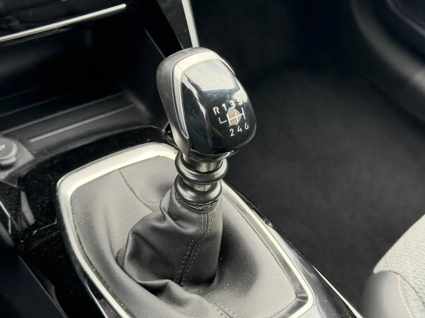 Le levier de vitesses manuel en gros plan de la Peugeot 208 1.2 100ch S&S Allure, intérieur noir.
