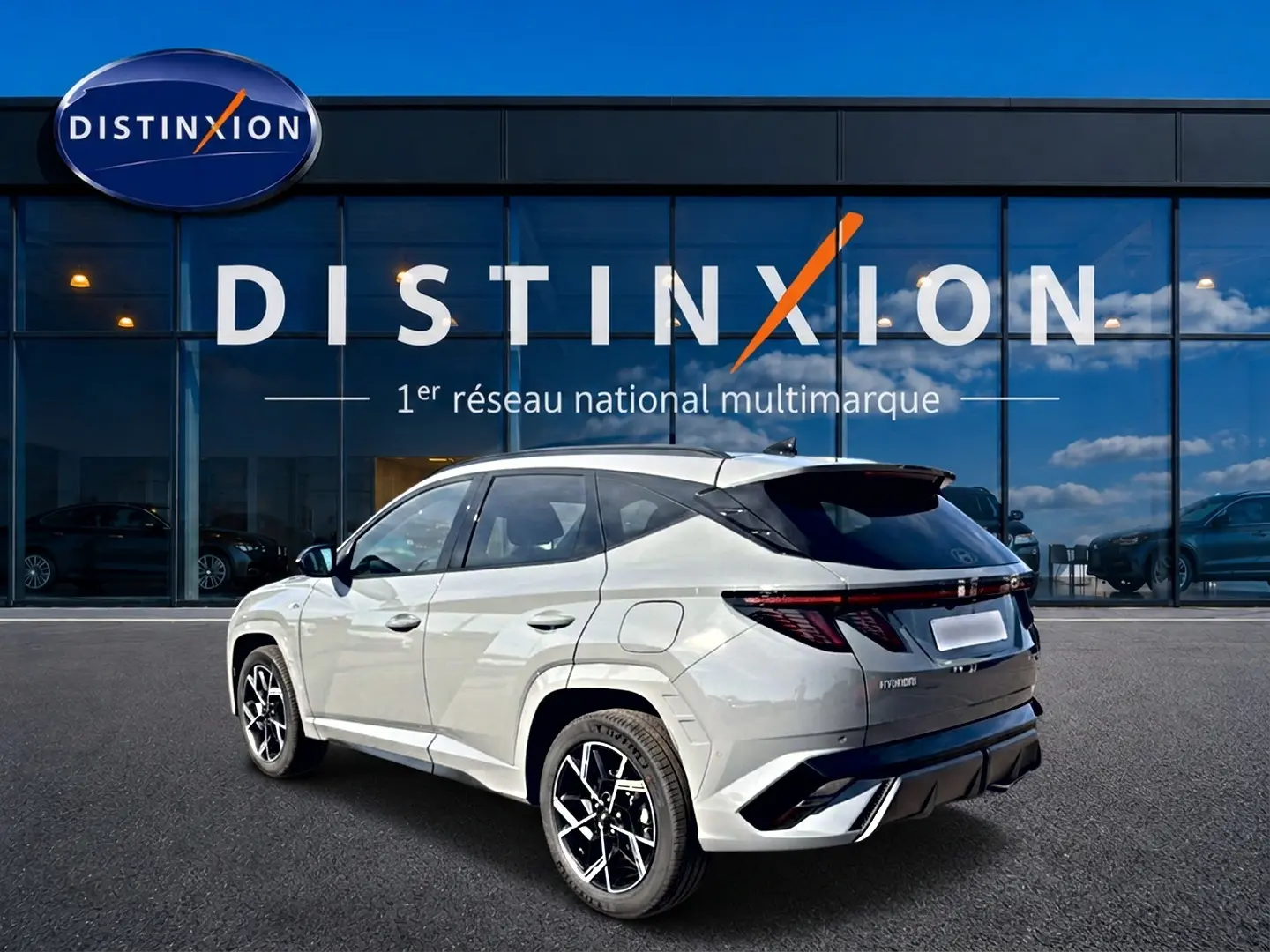 Hyundai Tucson 2026 gris shadow en 3/4 arrière droit, avec jantes alu noires et feux arrière LED allumés.