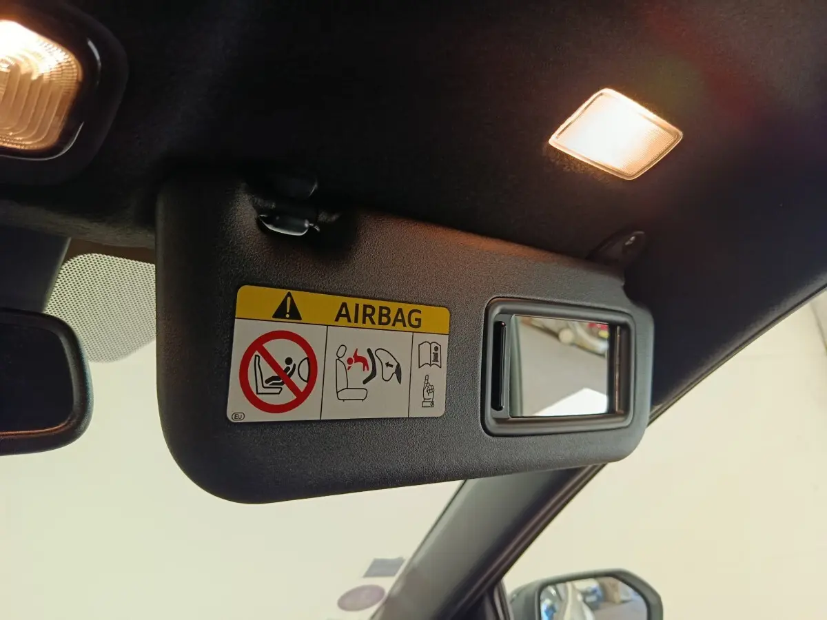 Détail du pare-soleil côté conducteur avec miroir et avertissement airbag dans une Toyota Yaris blanche 2022.