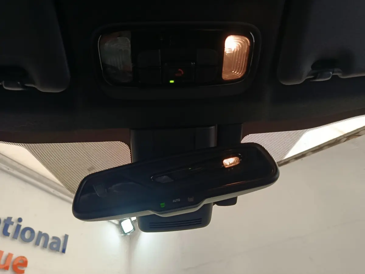 Vue intérieure centrée sur le rétroviseur intérieur avec éclairage, d'une Toyota Yaris Hybride blanche de 2022.