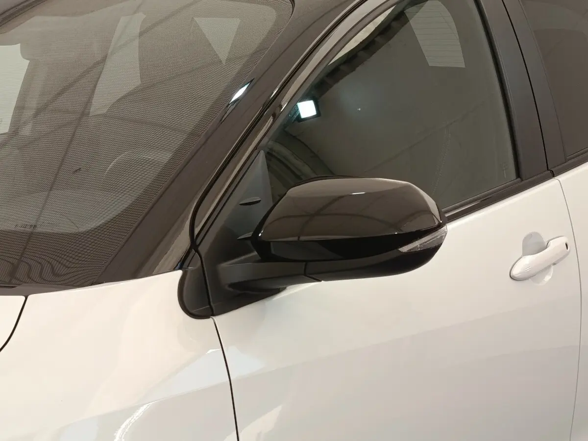 Vue rapprochée du rétroviseur noir côté conducteur sur la porte blanche d’une Toyota Yaris Hybride 2022.