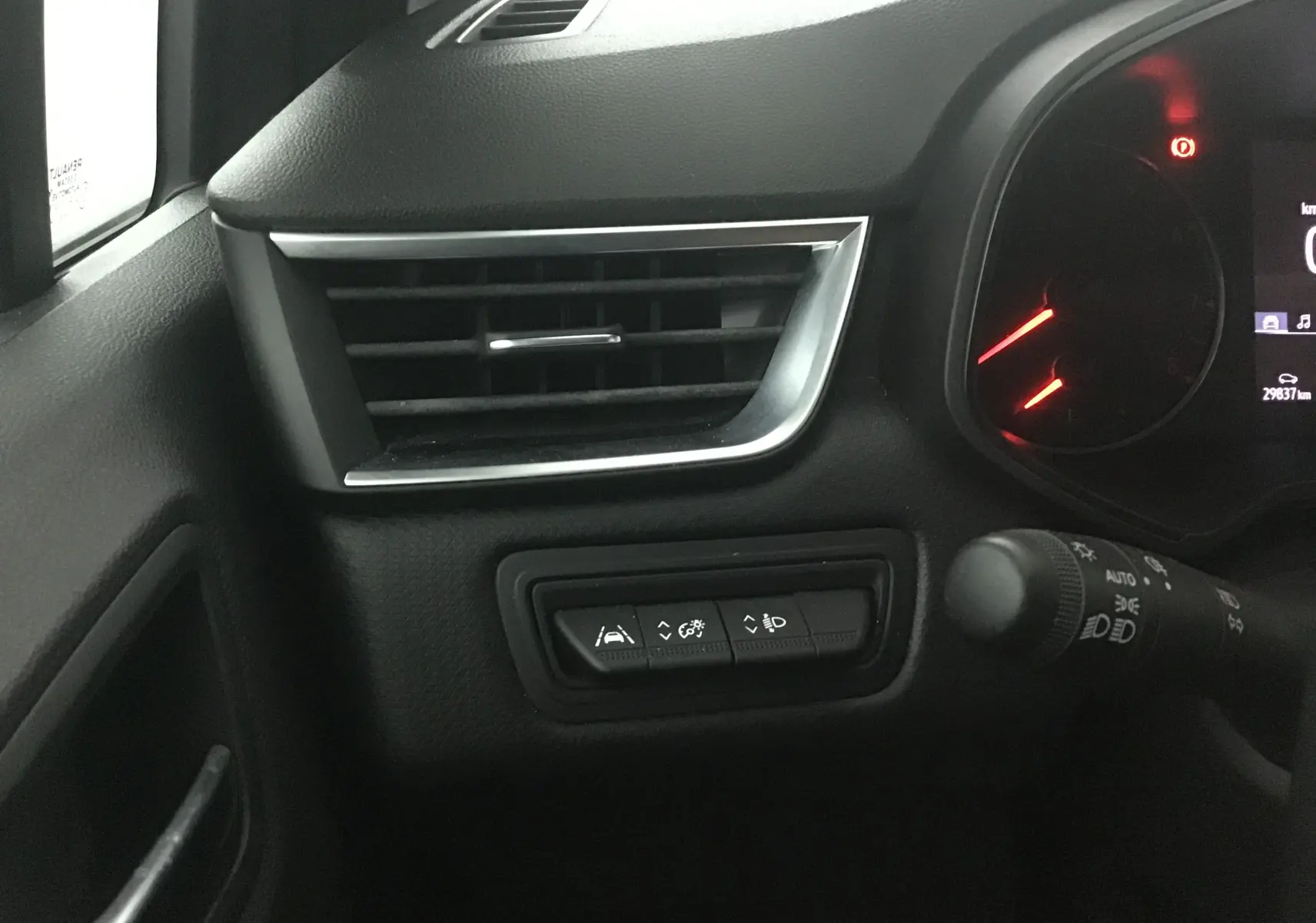 Détail du tableau de bord côté gauche de la Renault Clio V gris platine, avec commandes d'assistance et ventilation.