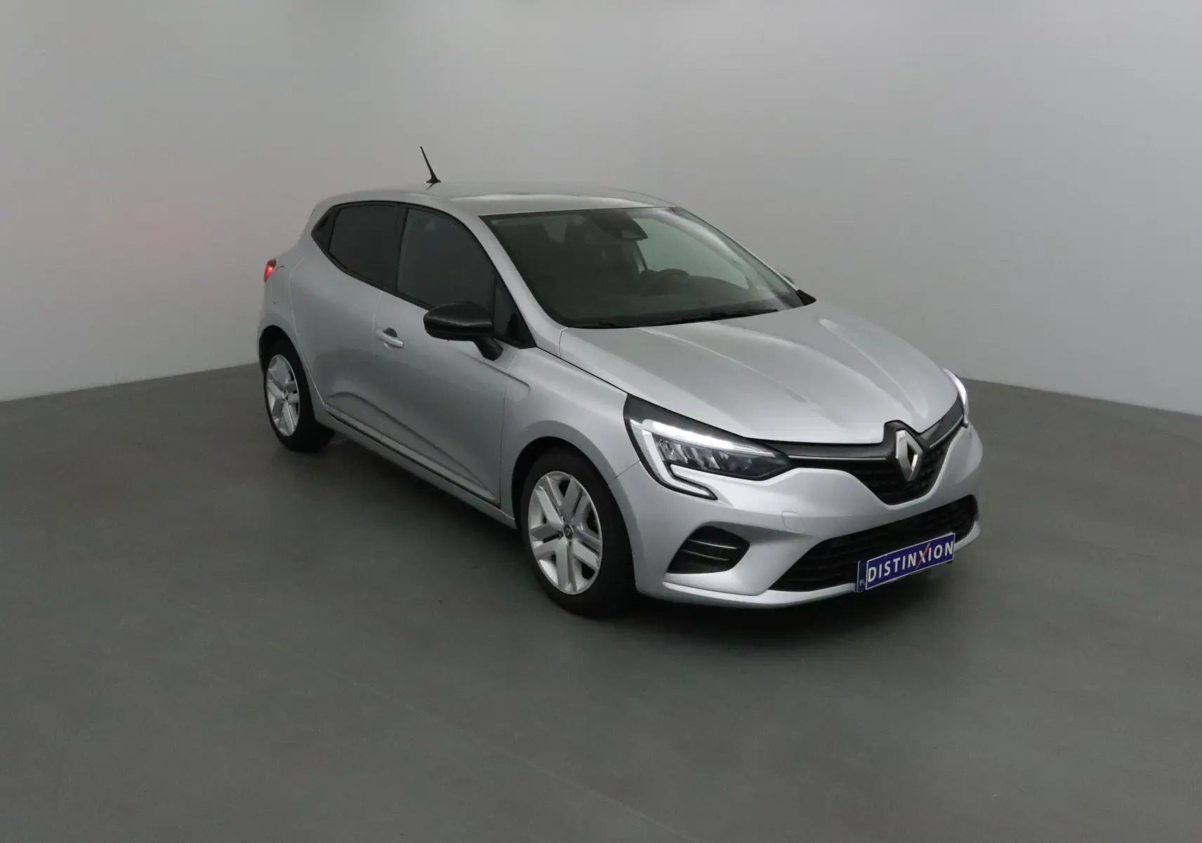 Renault Clio V gris platine vue 3/4 avant droit, avec phares LED et calandre noire distinctive.