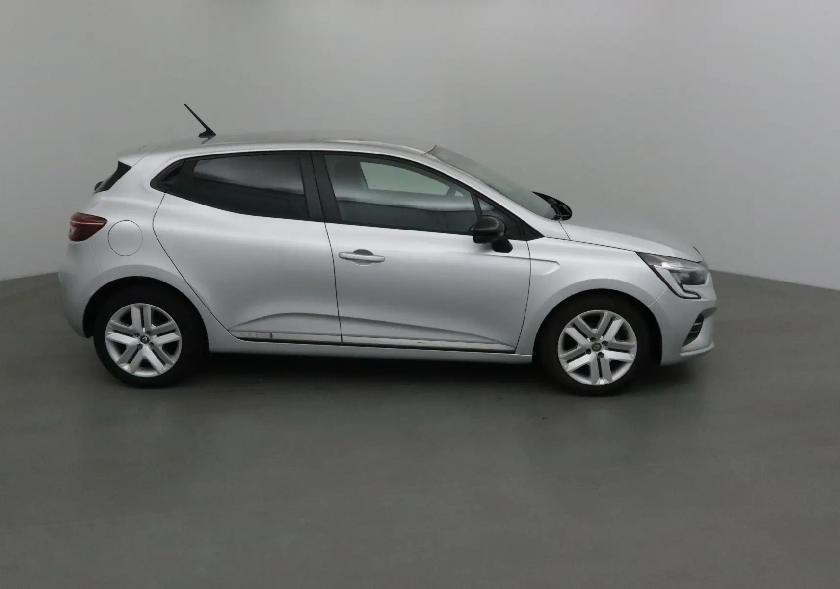 Renault Clio V gris platine vue de profil côté gauche, compacte avec jantes alliage et vitres teintées.