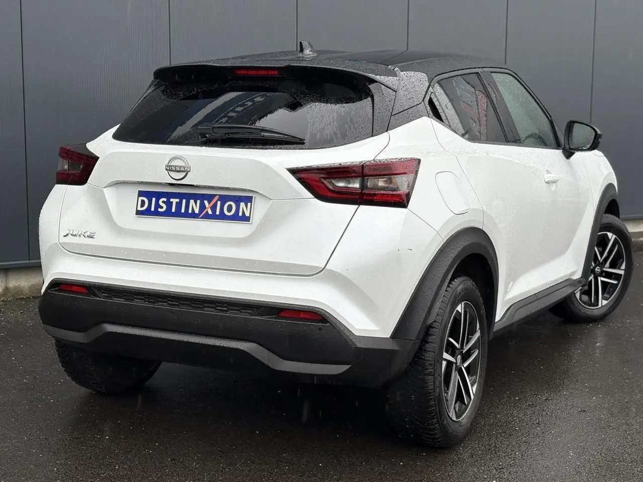 Nissan Juke blanc nacré vu en 3/4 arrière droit, avec toit noir et jantes alliage 17 pouces.