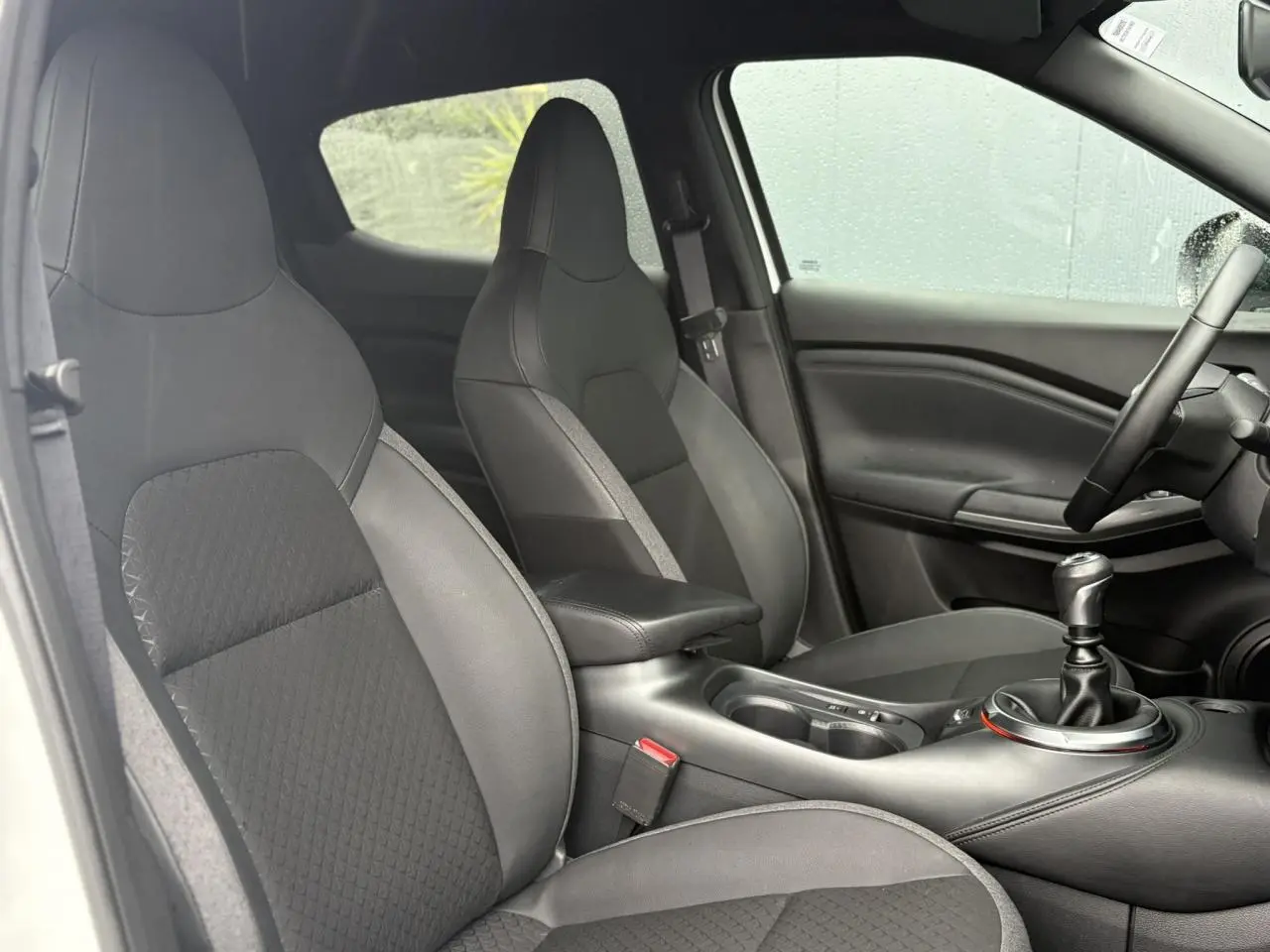 Intérieur du Nissan Juke 2025 montrant les sièges avant en cuir noir et la boîte manuelle côté droit.