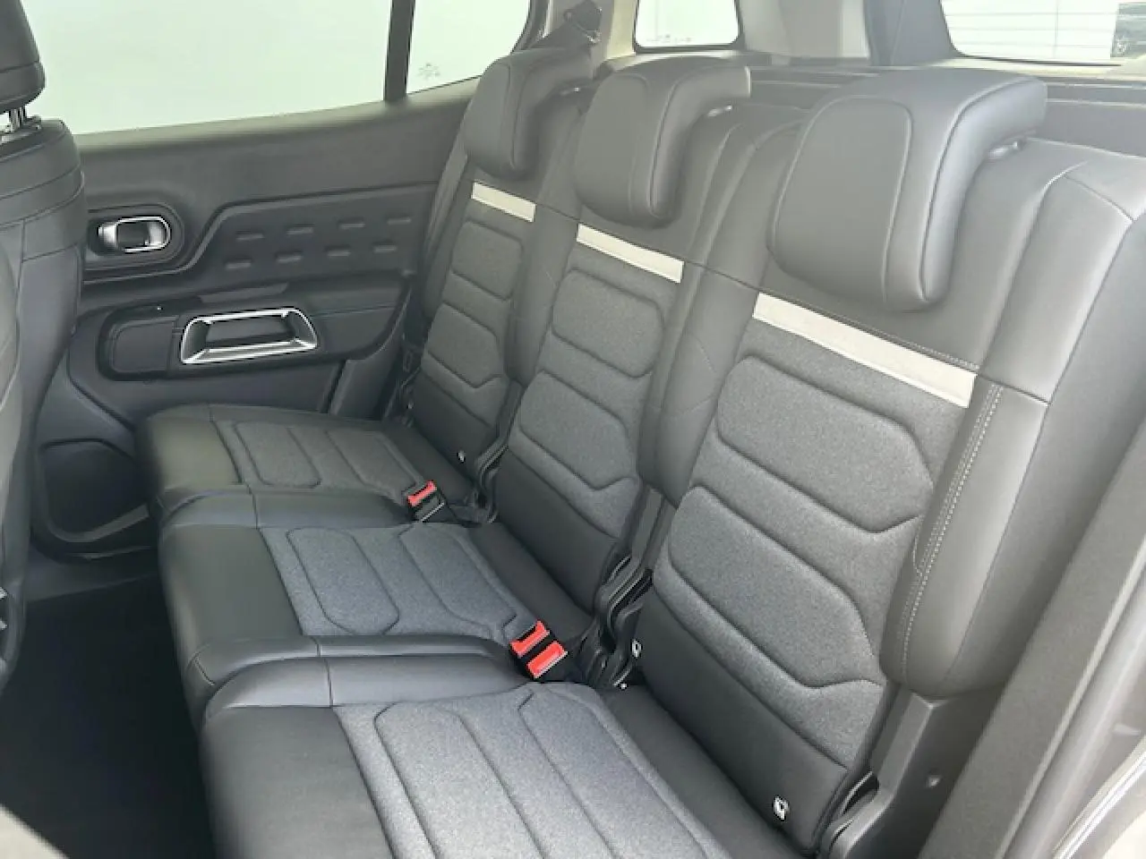 Vue latérale des trois sièges arrière indépendants gris foncé du Citroën C5 Aircross 2025 avec détails en tissu et cuir.