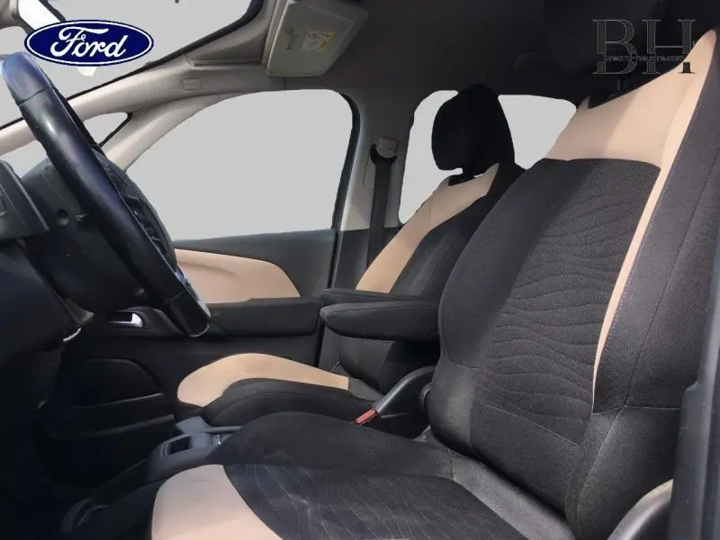 Vue intérieure côté conducteur de la Citroën C4 Picasso 2016 avec sièges bicolores beige et noir et accoudoir central.