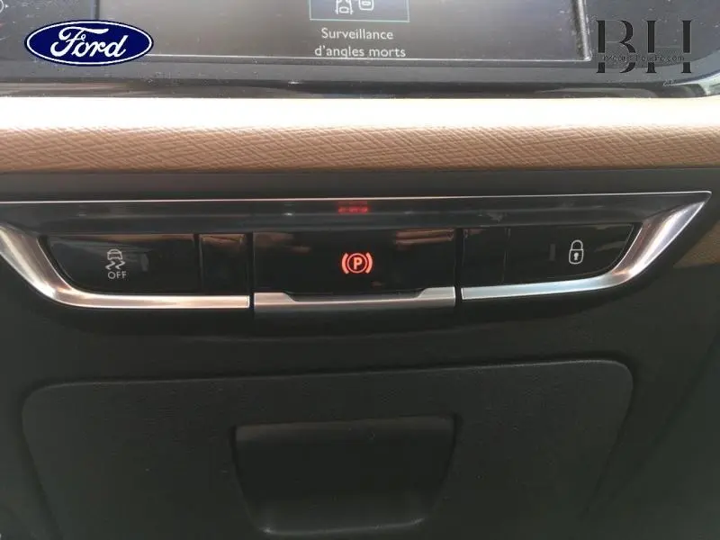 Gros plan sur la console centrale de la Citroën C4 Picasso gris Shark, avec boutons de frein à main électrique et verrouillage.