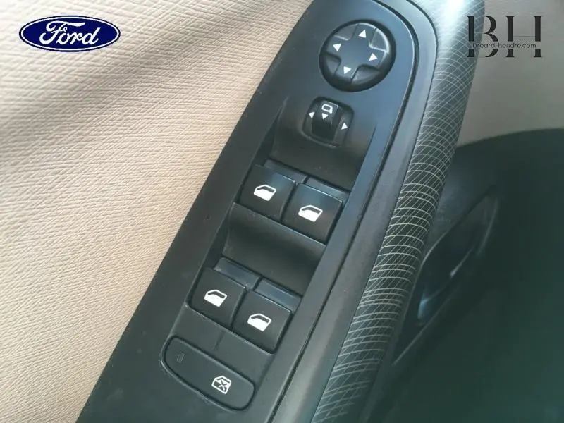 Vue rapprochée des commandes électriques des vitres et rétroviseurs côté conducteur d'une Citroën C4 Picasso gris Shark.