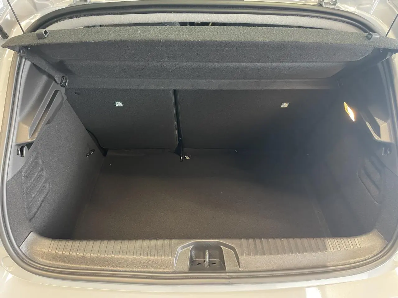 Coffre ouvert vu de l'arrière d'une Renault Clio 1.5 Blue dCi 2025 gris Rafale, intérieur noir et éclairage latéral.