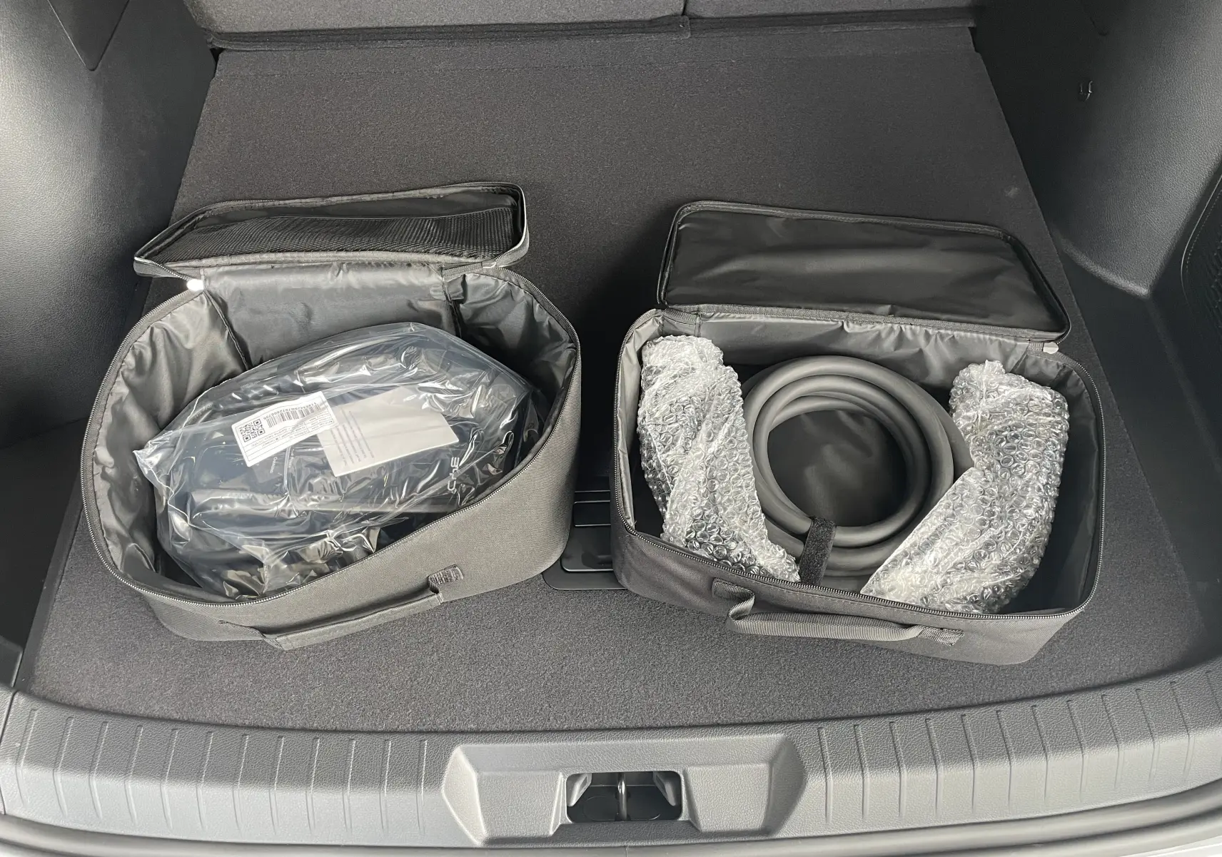 Vue du coffre du BYD SEAL U 2025 avec deux sacs de rangement contenant câbles de recharge et accessoires.